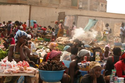 Women selling food stuff next to heap of garbage in Luanda