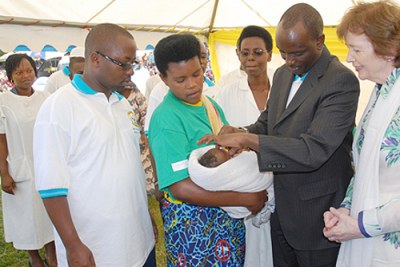 Le ministre de la santé rwandaise  Dr. Richard Sezibera qui administre un vaccin anti polio à un nourisson en présence de Mary Robinson représentante de GAVI en Afrique.