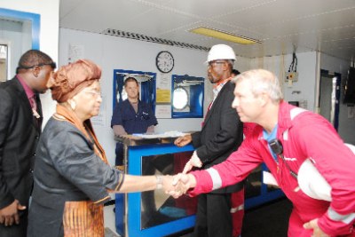 President Sirleaf meets an oil worker during a tour of an exploration rig (file photo).
