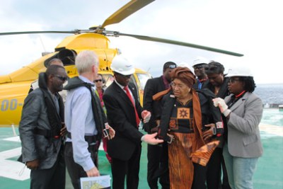 President Sirleaf being assisted on a tour of an oil rig.