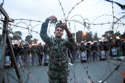 An Egyptian soldier sets up a wire fence in front of the presidential palace.