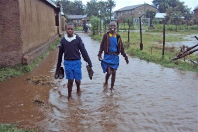 File Photo: Children walk on submerged foot paths as a result of flash floods.