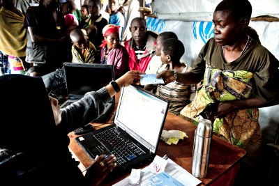 Des équipes du HCR remettant des cartes d'identifications à une congolaise qui s'est réfugiée avec toute sa famille en Ouganda