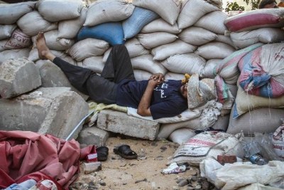 A supporter of Egypt's ousted President Mohammed Morsi sleeps by sand barriers set up by protesters around Raba'a square in Cairo (file photo).
