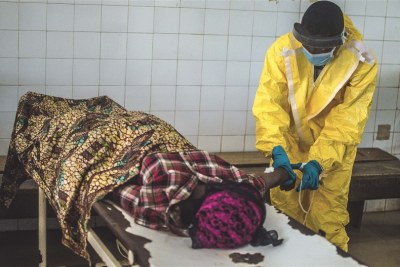 A government health worker in the MOH-led Kenema Ebola Treatment Centre in Sierra Leone attends to a victim. July 2014.