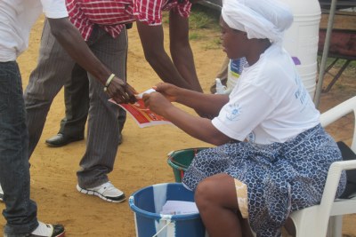 Women volunteers pray against Ebola while distributing fliers to passersby and asking them to wash their hands.