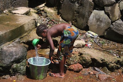 A young girl collects water from a rubbish-filled water hole (file photo).
