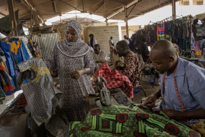 Une femme parle à un tailleur sur un marché à Gao, au Mali