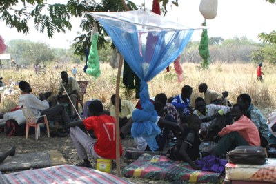 South Sudanese refugees under a tree which also shelters them at night.