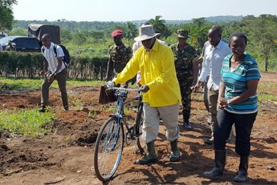 Museveni pushing his bicycle uphill to take water to the garden