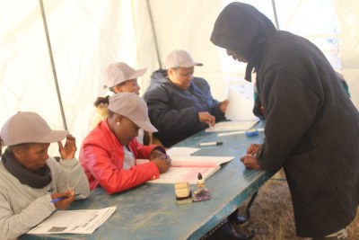 Officials assist a voter in Lesotho.