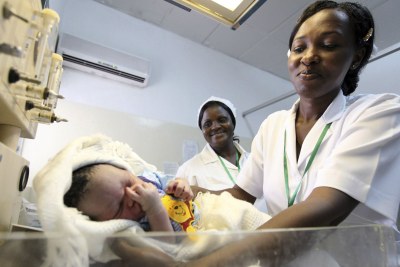 A nurse weighs a baby.