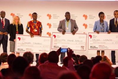Dr. Conrad Tankou, Rachel Sibande and Dr. Abdoulaye Diallo stand on the stage at NEF holding the U.S.$25,000 checks that they won for their innovation prizes.