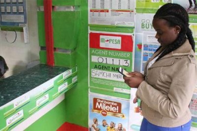 A woman withdraws money from an M-Pesa outlet in Nyeri (file photo).