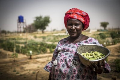 Une femme au Mali avec des légumes qu'elle a récoltés.
