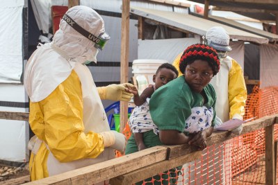 A health worker checks a child potentially infected with Ebola being carried on the back of a caregiver at the Ebola Treatment Centre of Beni, North-Kivu province, Democratic Republic of Congo in March 2019.