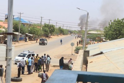 Residents are pictured on the streets of Mandera town as smoke rises from explosions in the neighbouring Bula Hawa town of Somalia, amid fighting between Jubbaland and FGS forces, on March 2, 2020.