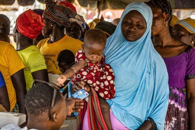Des femmes font la queue pour recevoir des cartes de bénéficiaires afin d'acheter de la farine enrichie pour prévenir la malnutrition à Kongoussi, au Burkina Faso.