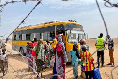 Returnees and refugees board a bus that will take them from the Joda border point to Renk transit center.