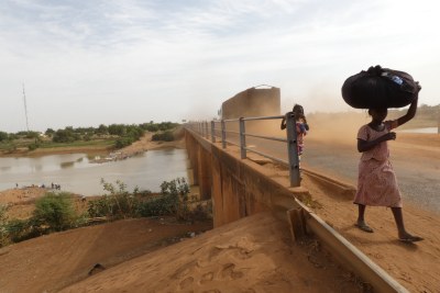 Deux jeunes piétons traversent le pont routier reliant le Mali à Kidira, au Sénégal. A gauche du pont à gué de la rivière Falémé, 2017.