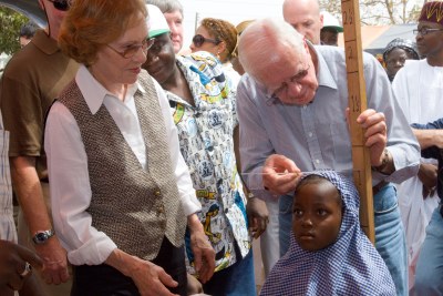 Former U.S. President Jimmy Carter and former First Lady Rosalynn Carter in Nasarawa North, Nigeria, measure a little girl's height to gauge the accurate medication needed to prevent schistosomiasis, a silent and destructive parasitic infection that leads to poor growth and impaired learning in children.